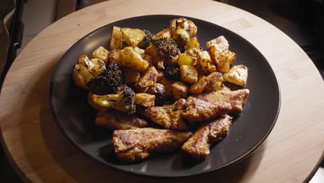 hand is arranging food on a plate, fried chicken with roasted vegetables