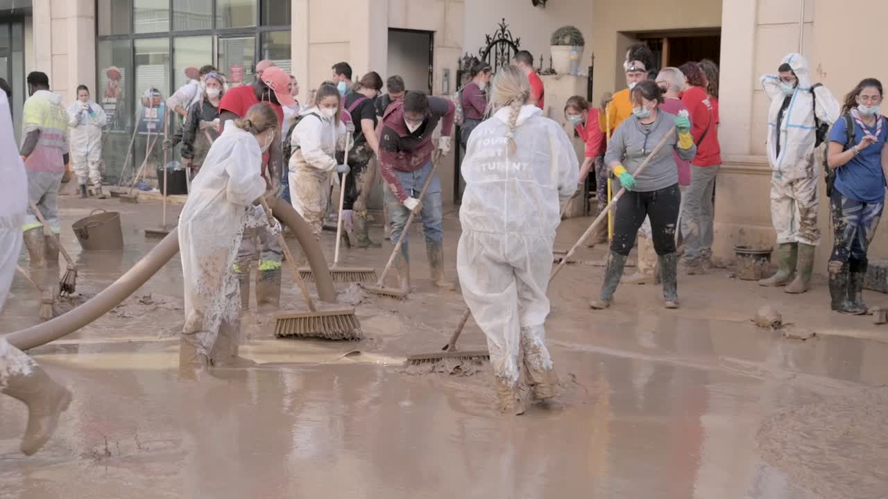 Volunteers wearing protective gear work together to clean up mud and debris after a DANA storm in Valencia