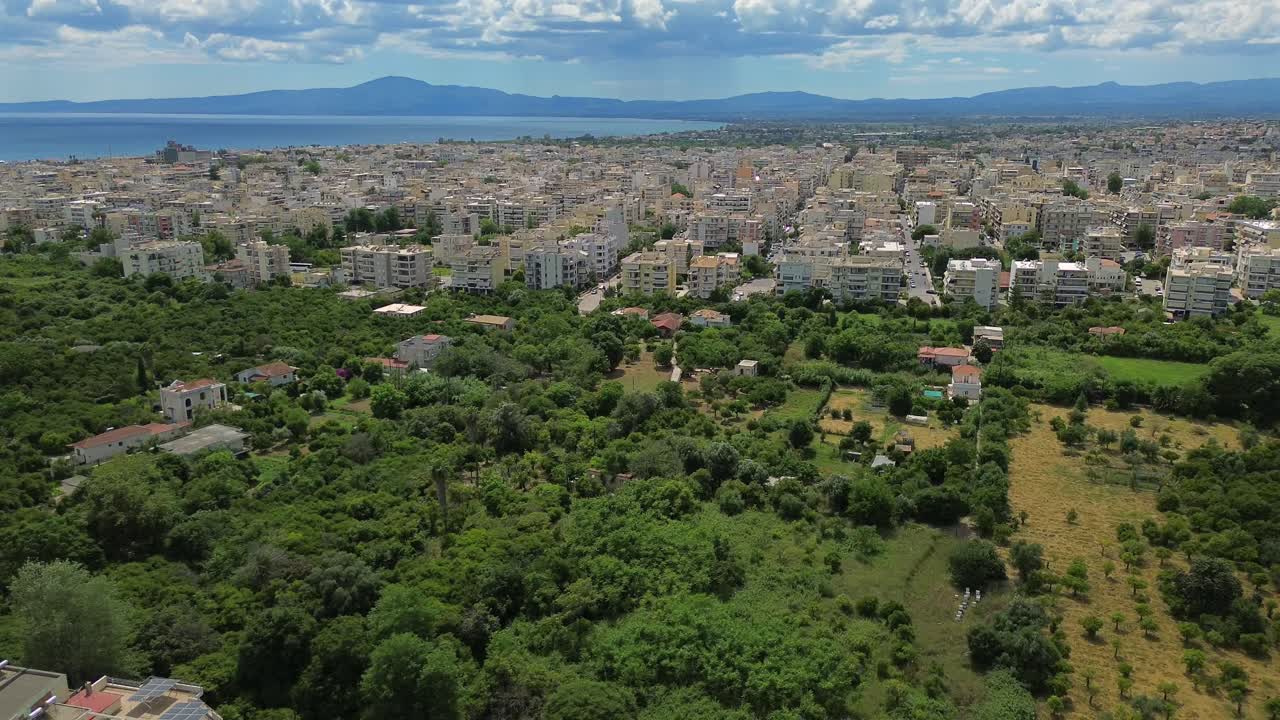 Aerial cityscape of Kalamata , beautiful white clouds on blue sky, green orchards on foreground , push out, tilt down revealing shot 4K
