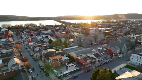 slow panoramic view of a city, including houses, businesses, industrial buildings, several city blocks bridges, a river and hills in the background at sunset