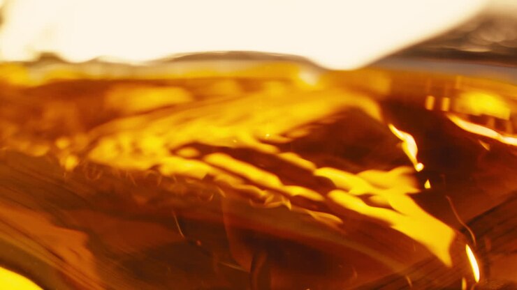 Orange or white wine bottle and glass against a sunset in a peaceful vineyard, pouring of ecological natural wine.