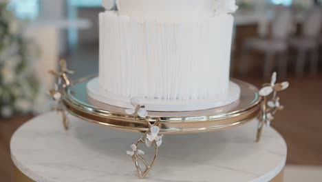 sleek white wedding cake with vertical lines on elegant gold stand with flower accents