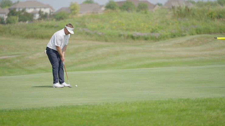 Golfista che esegue un putt sul green di un campo da golf
