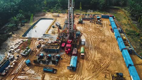 Cinematic-Onshore-Drilling-and-Workover-Rig-structure-and-Rig-equipment-for-oil-exploration-and-exploitation-in-the-middle-of-jungle-surrounded-by-palm-oil-trees-during-sunset-time