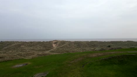 drone slowly rises over grassy dunes revealing winterton beach and ocean view