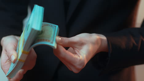 a caucasian businesswoman flips through a stack of paper cash