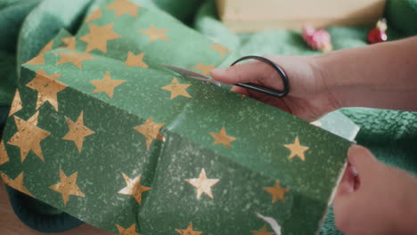 mãos cortando papel de embrulho verde em forma de estrela durante o natal em casa