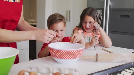 Feliz-Madre-Caucásica,-Hija-E-Hijo-Rompiendo-Huevos,-Horneando-Juntos-En-La-Cocina