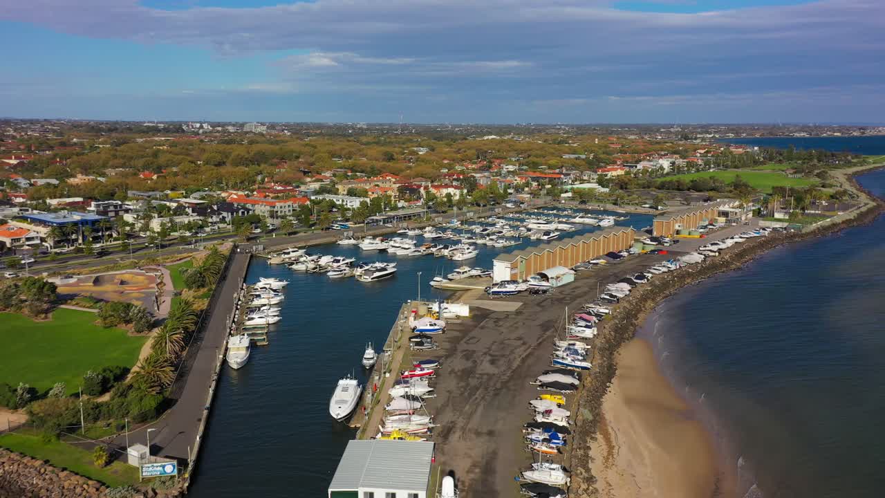 Aerial footage over the seas of St Kilda Beach, with Melbourne's CBD skyline in the horizon on a beautiful autumn windy afternoonlighthouse and the piers docking hundreds of boats