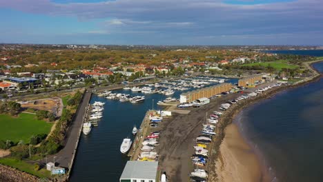 Aerial-footage-over-the-seas-of-St-Kilda-Beach,-with-Melbourne's-CBD-skyline-in-the-horizon-on-a-beautiful-autumn-windy-afternoonlighthouse-and-the-piers-docking-hundreds-of-boats