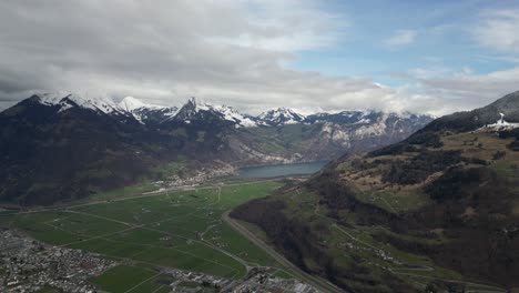 Eine-Luftaufnahme-Von-Glarus-In-Der-Schweiz-Zeigt-Die-Umgebung,-Umgeben-Von-Schneebedeckten-Berggipfeln-Und-Einem-Ruhigen-See,-Der-Die-Malerische-Kulisse-Ergänzt