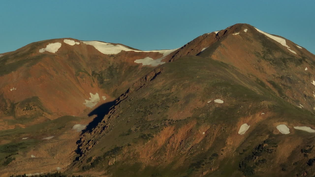 Aerial cinematic drone sunrise sunlight early morning shadows Grays and Torreys 14er Peaks Rocky Mountains Colorado stunning landscape view mid summer snow on top loveland zoom to the right movement