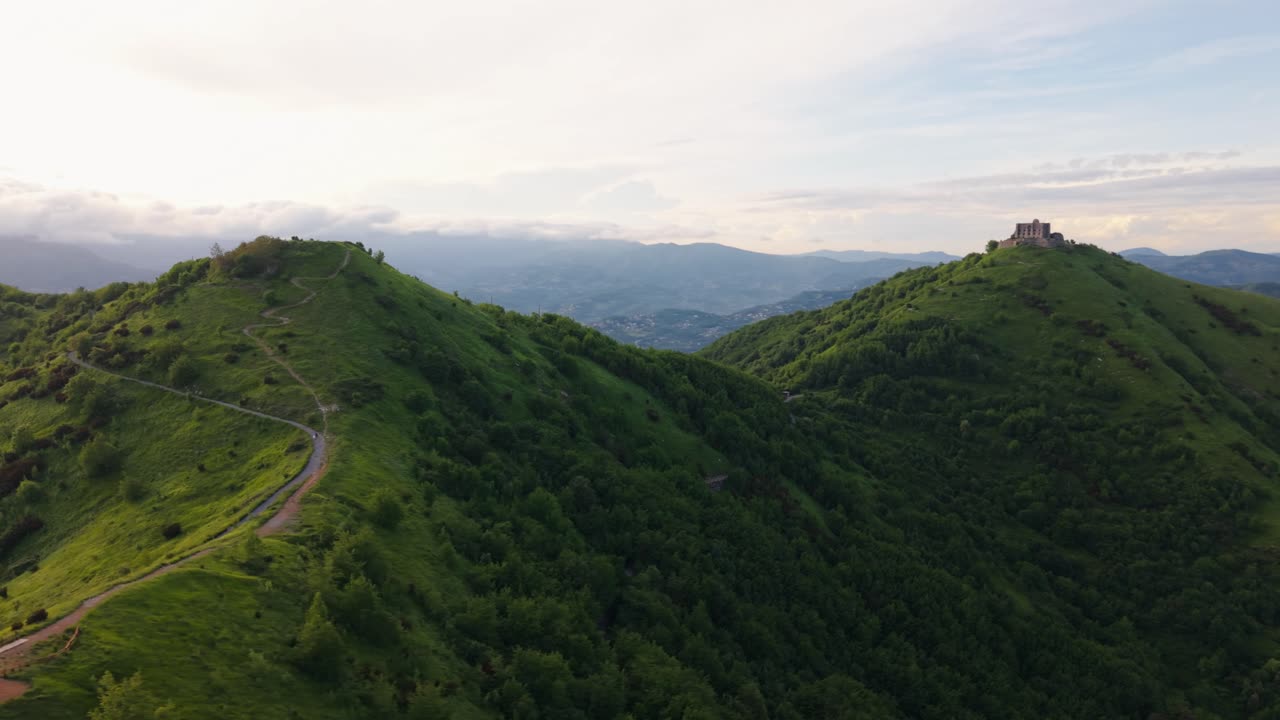 Ancient hilltop fort in Italy surrounded by green hills at golden hour