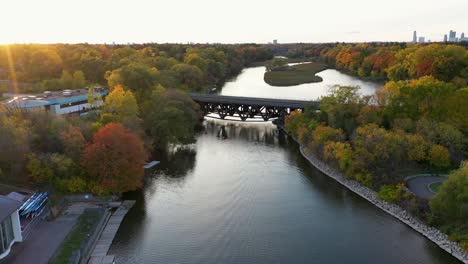 drone flying toward a bridge crossing a mississauga river at sunrise