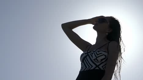 woman in swimsuit silhouette against bright sky