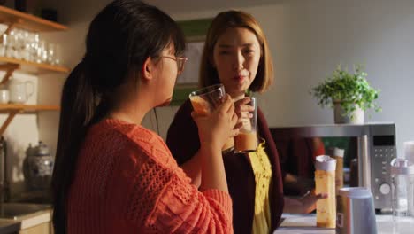 아시아 어머니와 딸이 부 ⁇ 에서 건강한 음료를 마시며 미소 짓고 있습니다.