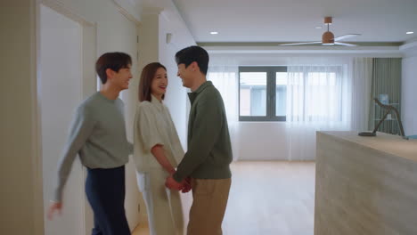 three friends or a couple visiting a new empty apartment