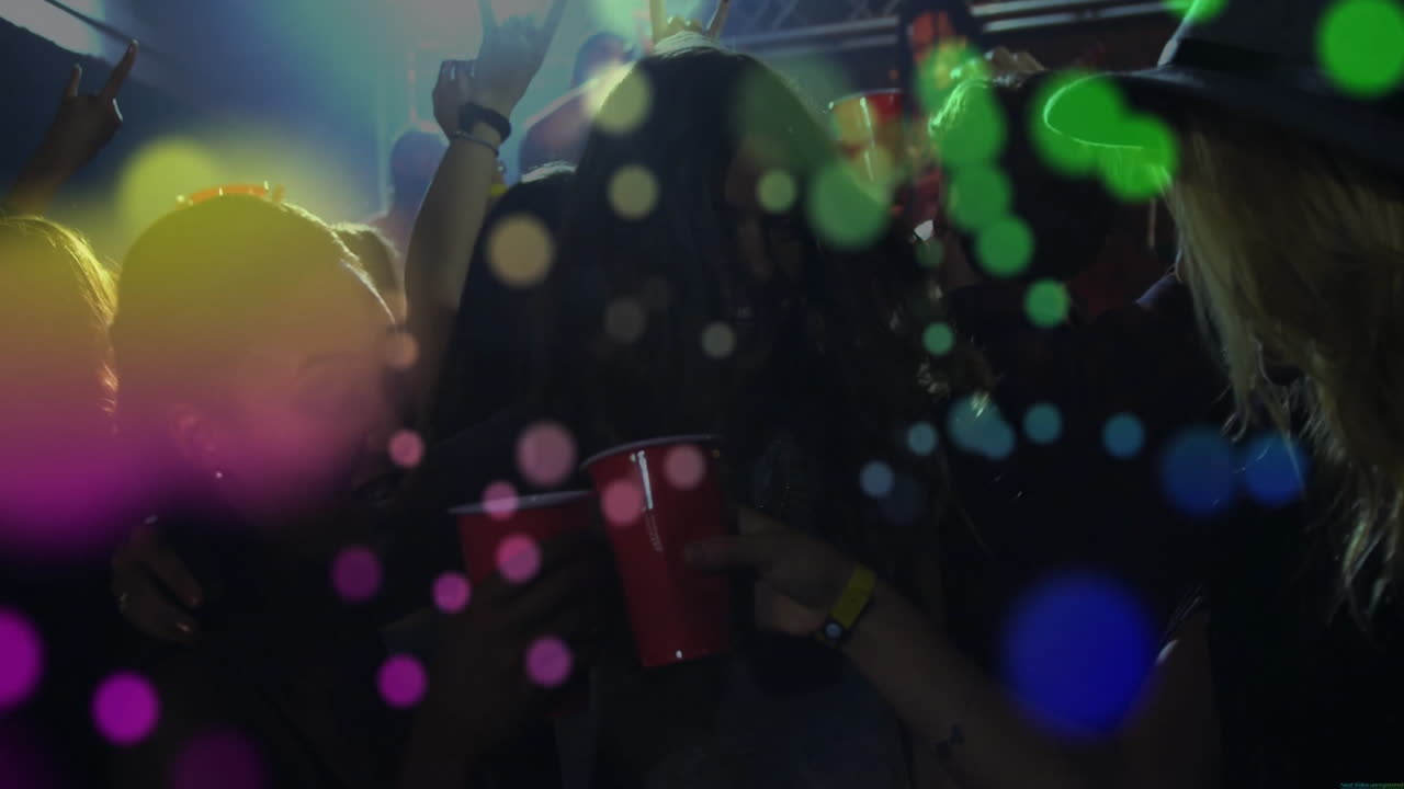 Amici con bicchieri rossi che ballano sotto le luci di una discoteca, con grafici aziendali animati e metriche
