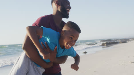 video of happy african american father and son having fun on beach