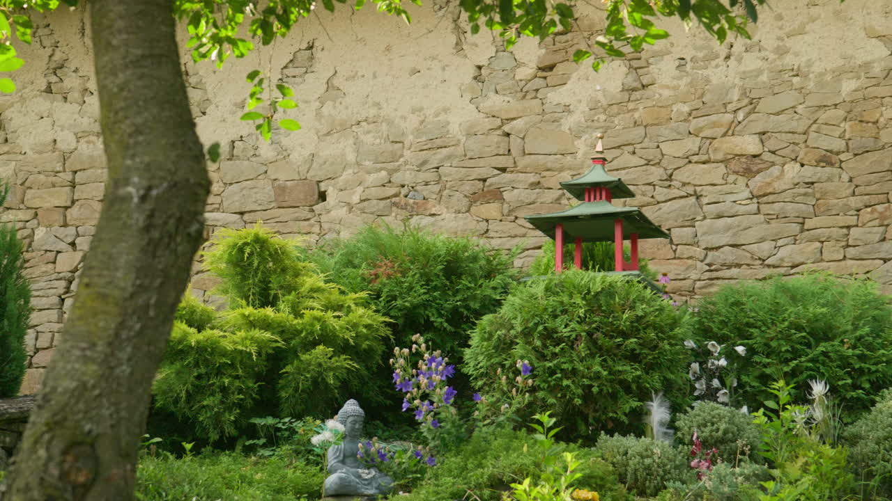 庭の低木と花々に囲まれた、装飾的な中国風のパゴダと仏像。