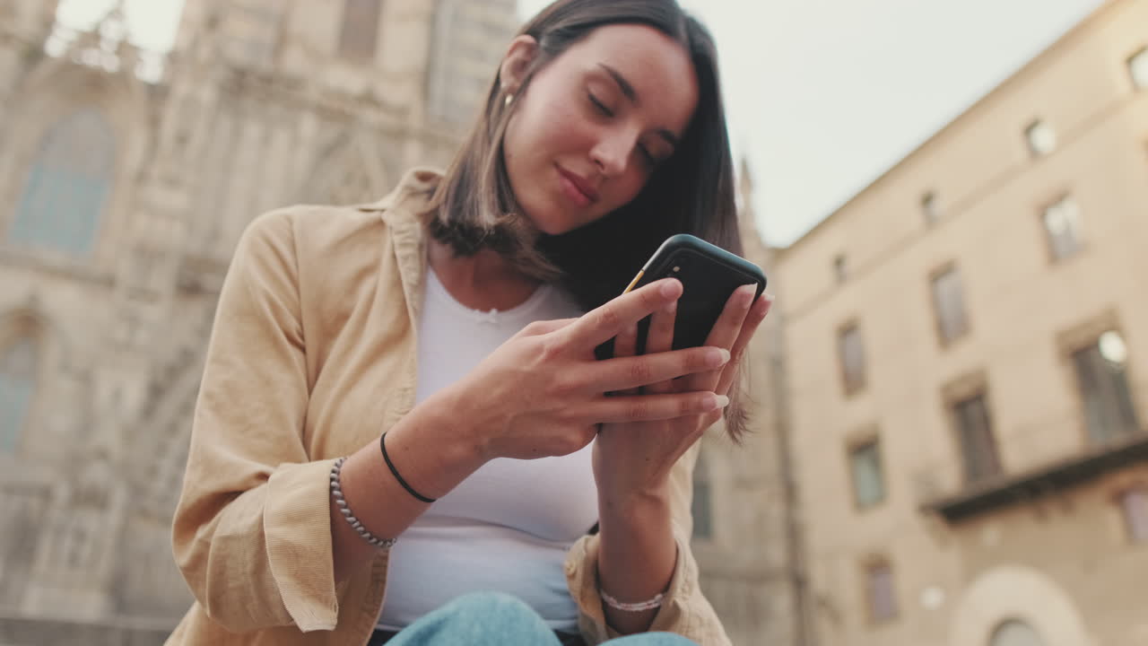 Giovane donna che usa lo smartphone all'aperto in una città europea