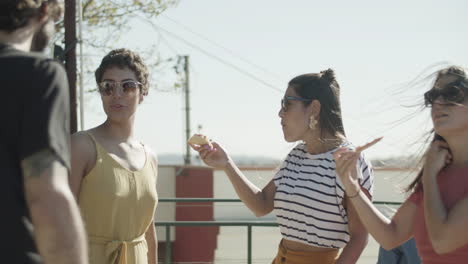 hombres y mujeres felices bailando y comiendo pizza en la fiesta de la azotea