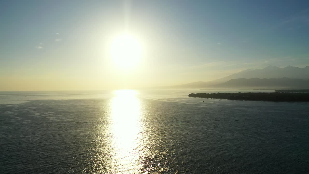 발리 해안선의 잔잔한 해수면 위에 반사되는 빛나는 하늘에 바다 지평선 아래로 지는 태양