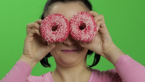 woman holding pink donuts over eyes