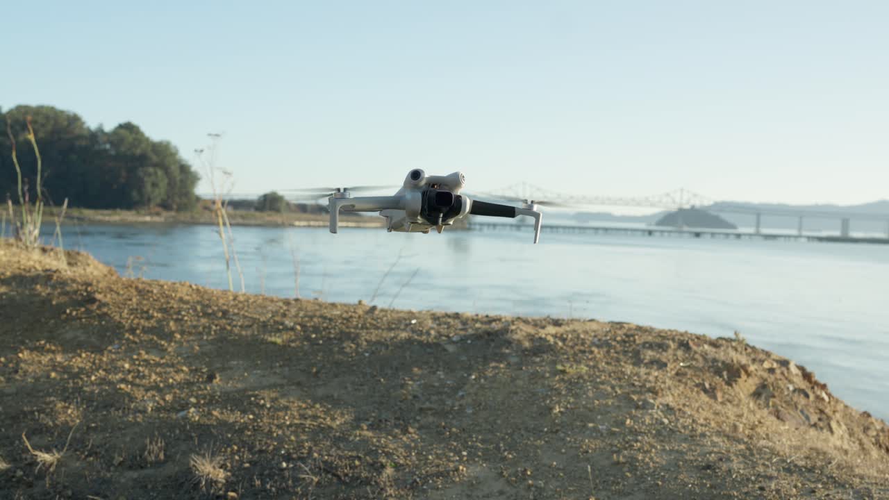 A lightweight drone hovers above the sandy hill while the Richmond–San Rafael Bridge stretches across the horizon, creating a calm coastal backdrop for the quiet flight