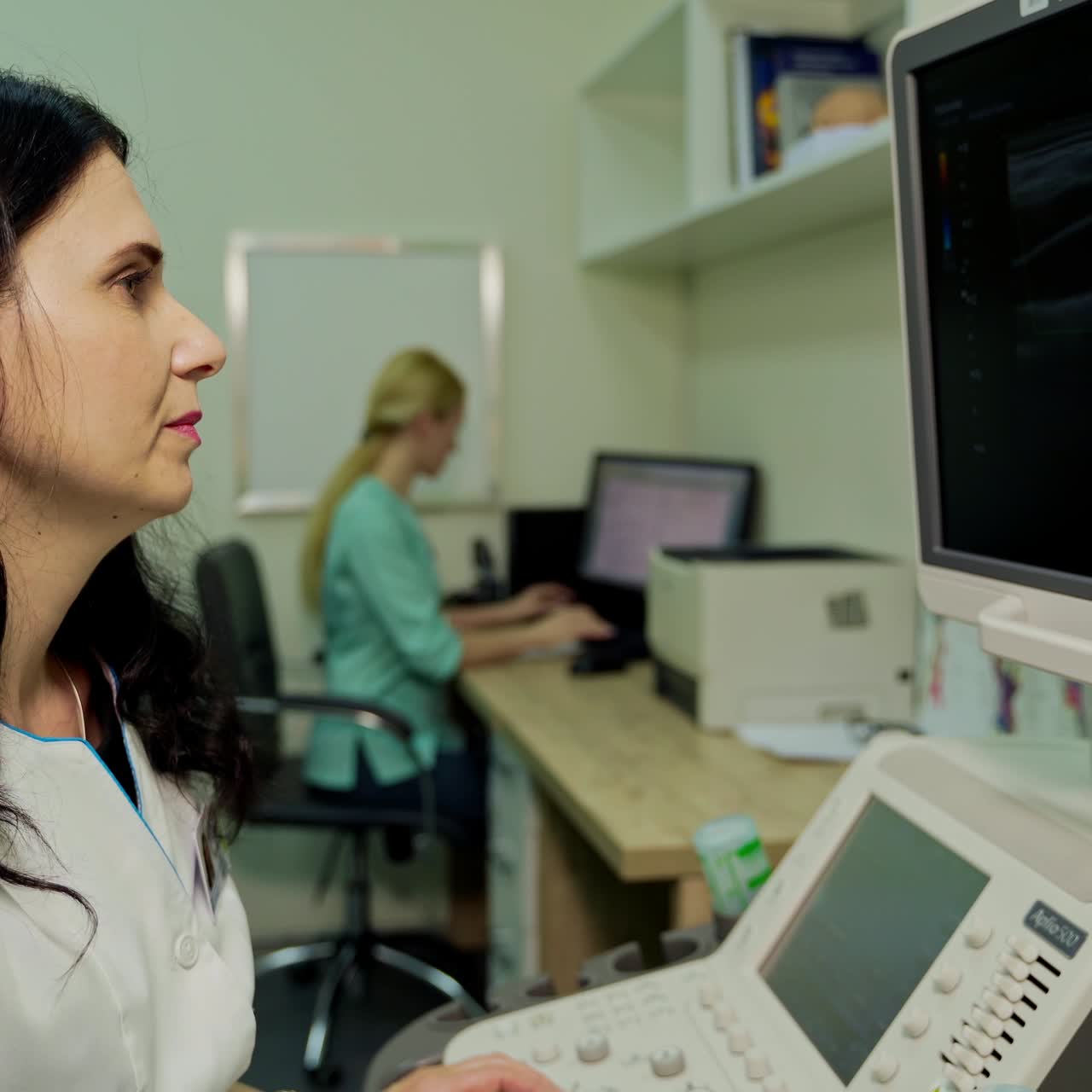 Medical specialist works with ultrasound apparatus. Professional woman doctor explaining results while doing ultrasound research in clinic.