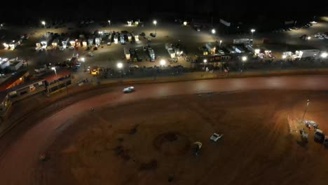 aerial footage of oval dirt track car racing at night