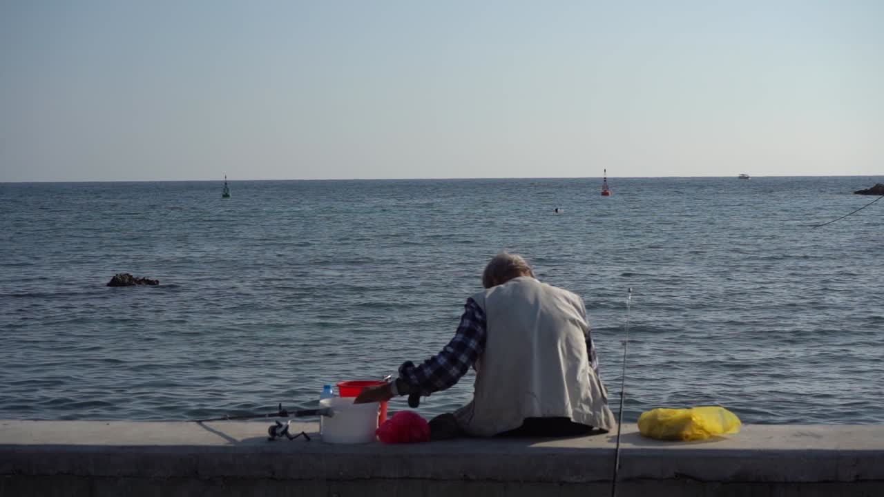 Αn old man is fishing in the calm sea .Τhe plan is fixed.