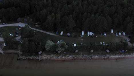 aerial view of vans and camping huts by the seaside with lush coniferous trees