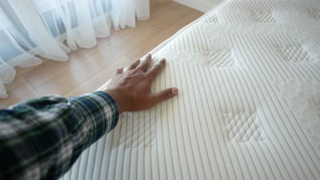 person's hand touching a mattress