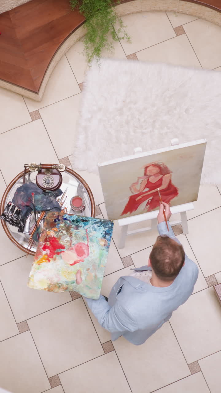 el artista pinta el vestido escarlata de la dama en el lienzo. el retratista del hombre deja pinceladas en la imagen de la mujer apasionada en la galería. trabaja con el modelo en la tienda de arte