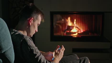 man using smartphone by the fireplace