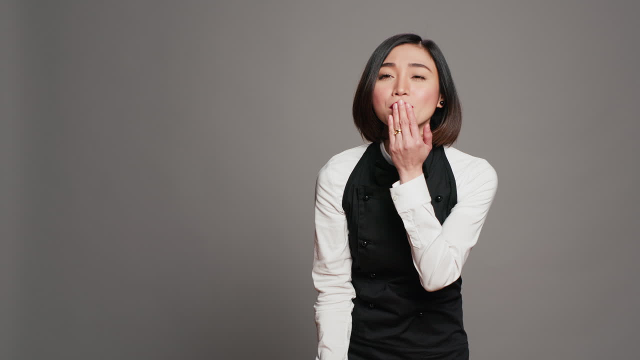 귀여운 유혹적인 웨이트리스가 카메라 앞에서 공기 키스를 불어넣습니다.