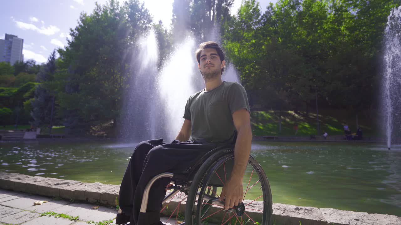 un joven guapo sentado en una silla de ruedas en la calle.
