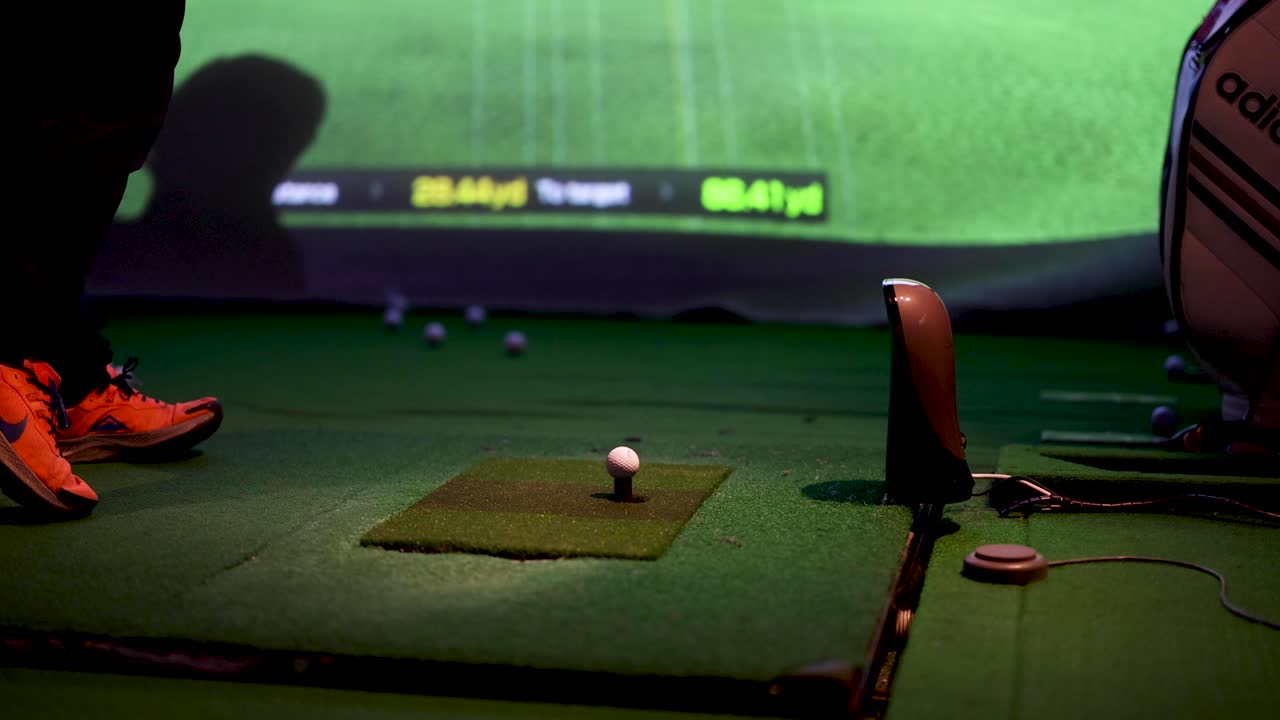 골퍼 가 실내 경기장에서 스 을 연습 하고 있다