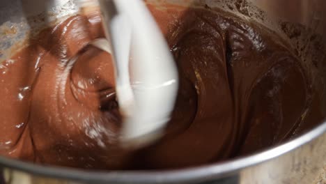 close up shot of cake batter being blended with a paddle attachment on a stand mixer