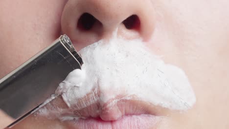 adult male delicately and patiently shaves moustache from his face