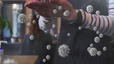 animation of coronavirus cells over caucasian female hairdresser disinfecting hands