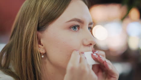 close-up of lady gently wiping her mouth with napkin, soft blur background featuring warm bokeh lights and a relaxed indoor setting