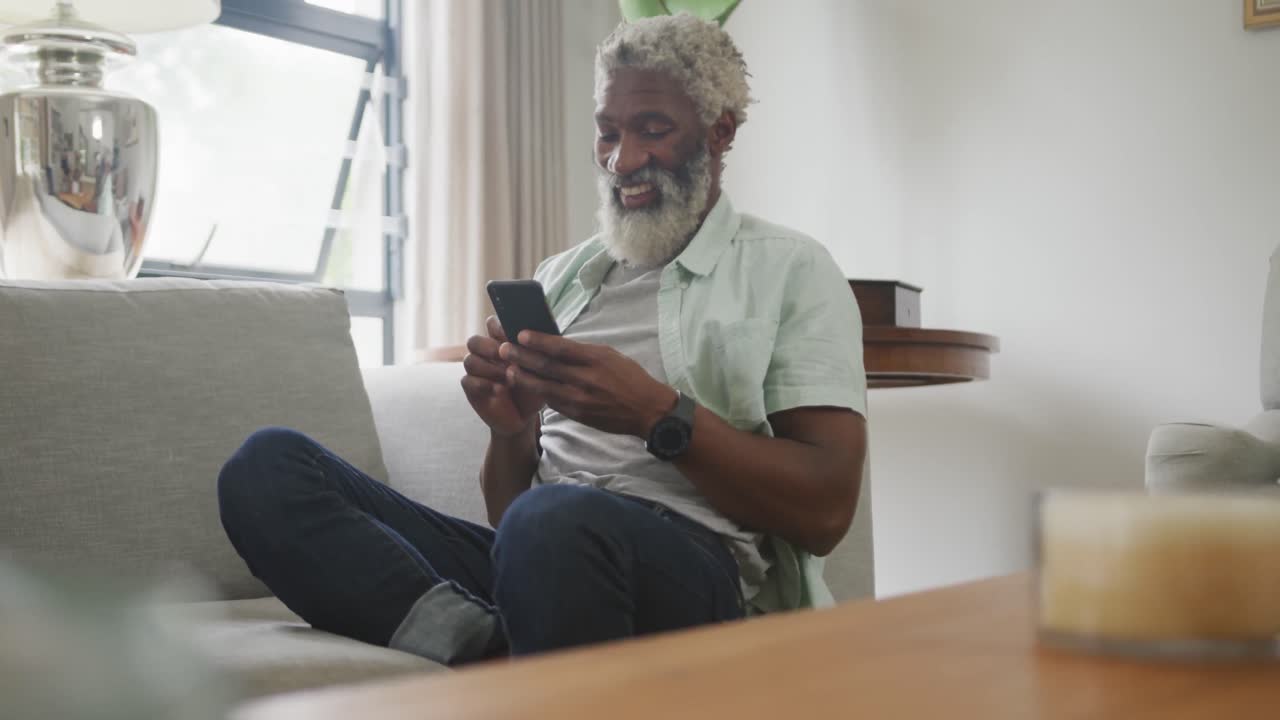 Video of happy african american senior man using smartphone