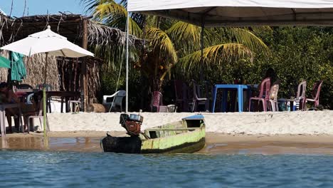 Slow-Motion-shot-of-a-small-motorboat-docked-on-the-tropical-Restinga-beach-near-the-tropical-coastal-town-of-Barra-do-Cunhaú-in-Rio-Grande-do-Norte,-Brazil-on-a-warm-sunny-summer-day