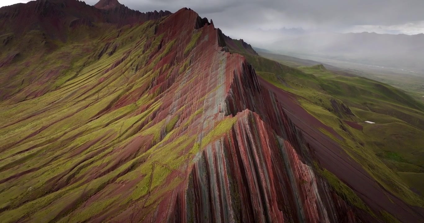 Formazioni rocciose striate costeggiano una cresta colorata a Pallay Punchu, la Montagna Arcobaleno, Perù; l'inclinazione verso l'alto del drone rivela scogliere mozzafiato