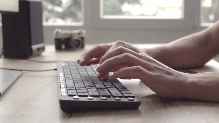 Tippen auf einer Tastatur. Mann tippt auf Computertastatur. Männerhand benutzt Computertastatur und Maus zum Tippen. Freiberuflicher Fotograf arbeitet am Computer.