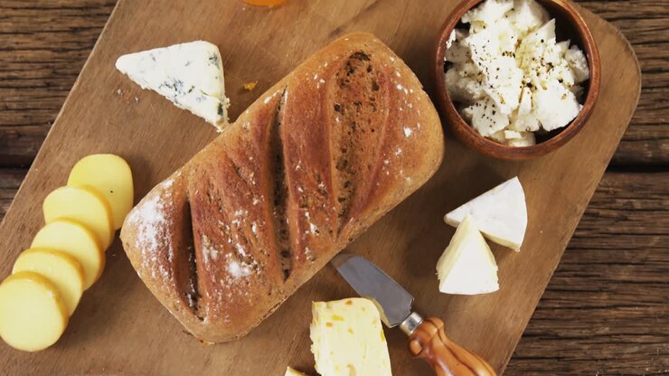 Loaf of bread with cheese, knife and jam