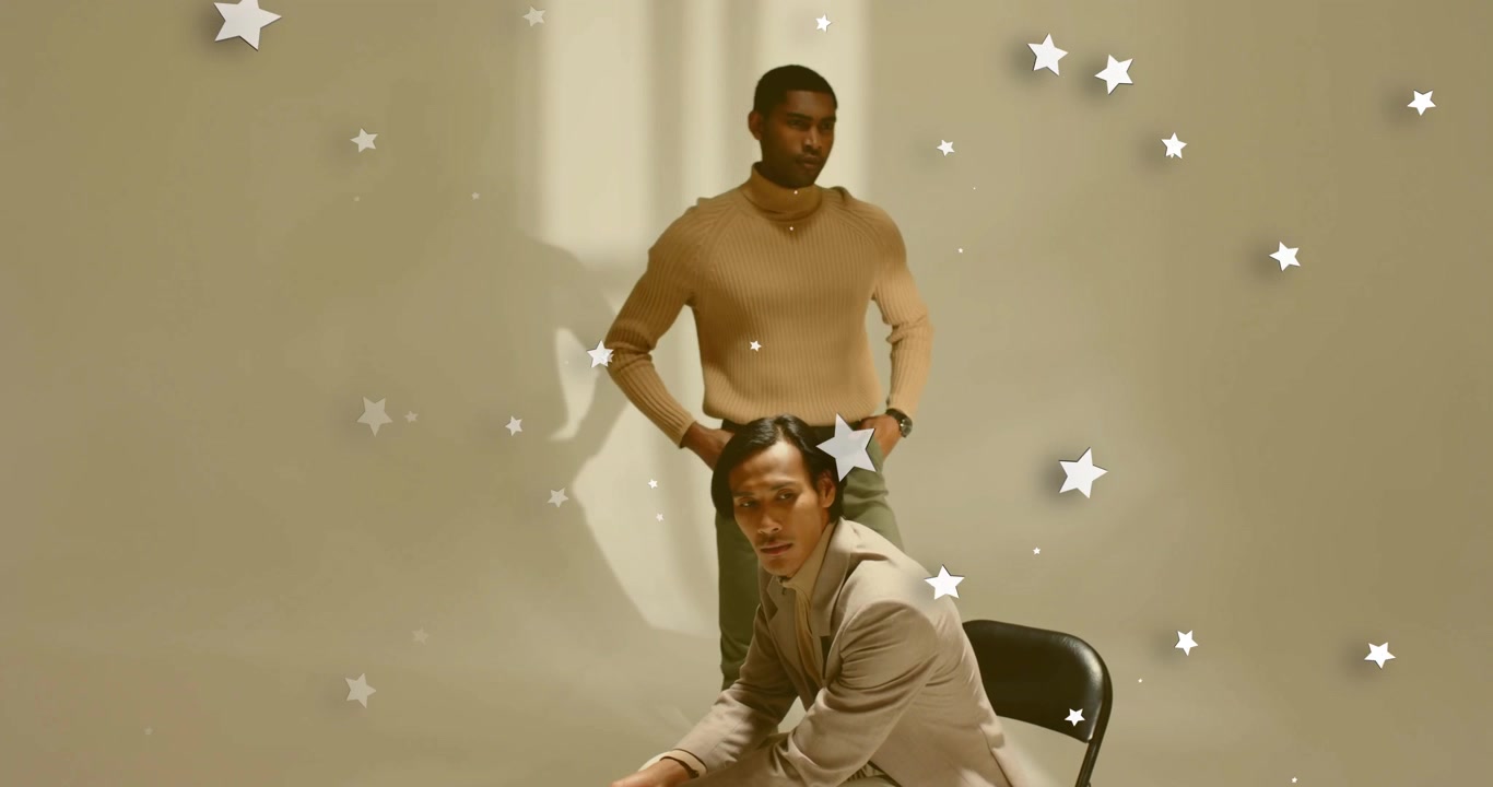 Two male models responding to star overlays appearing during advertising shoot by rising from chair