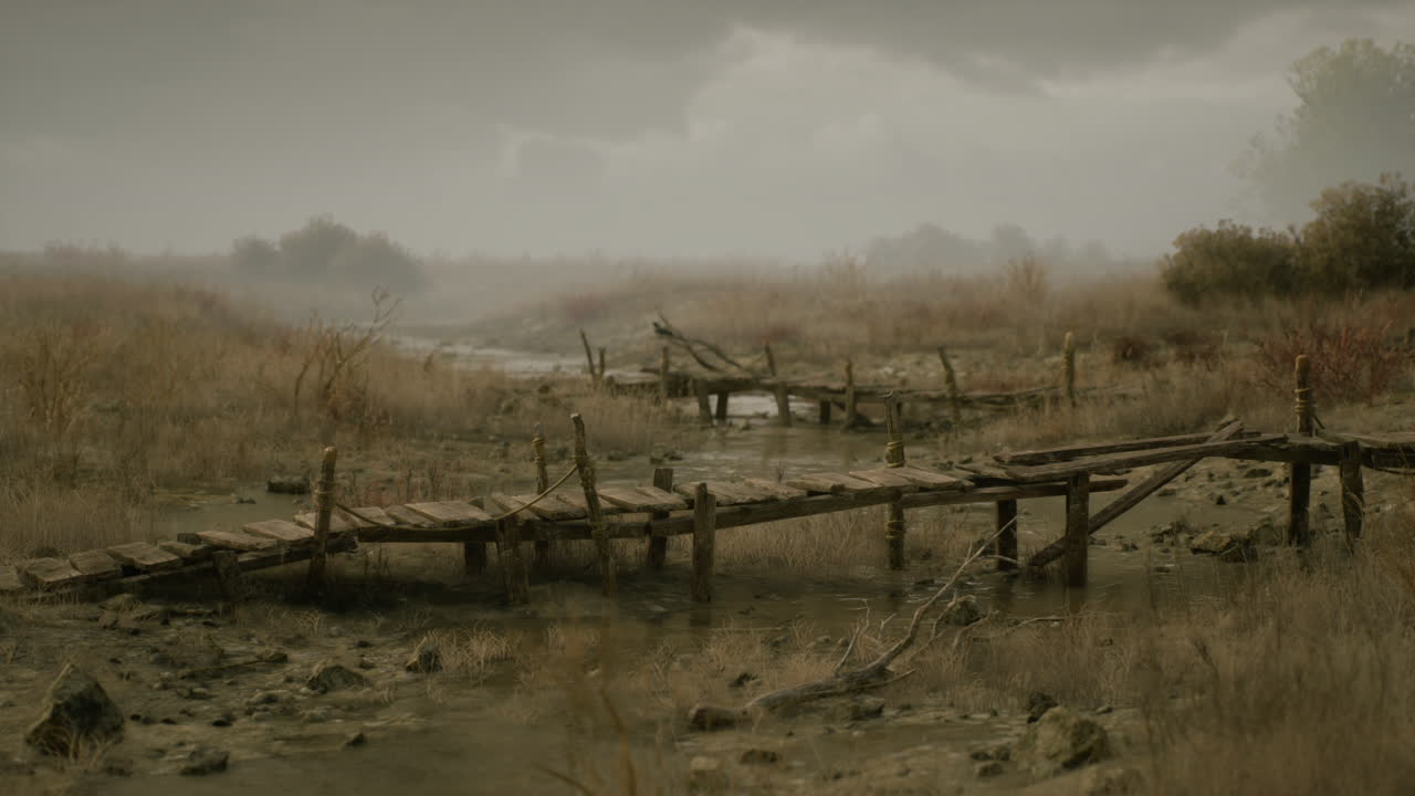 Un vecchio ponte di legno attraversa un letto di torrente asciutto sotto un cielo coperto.